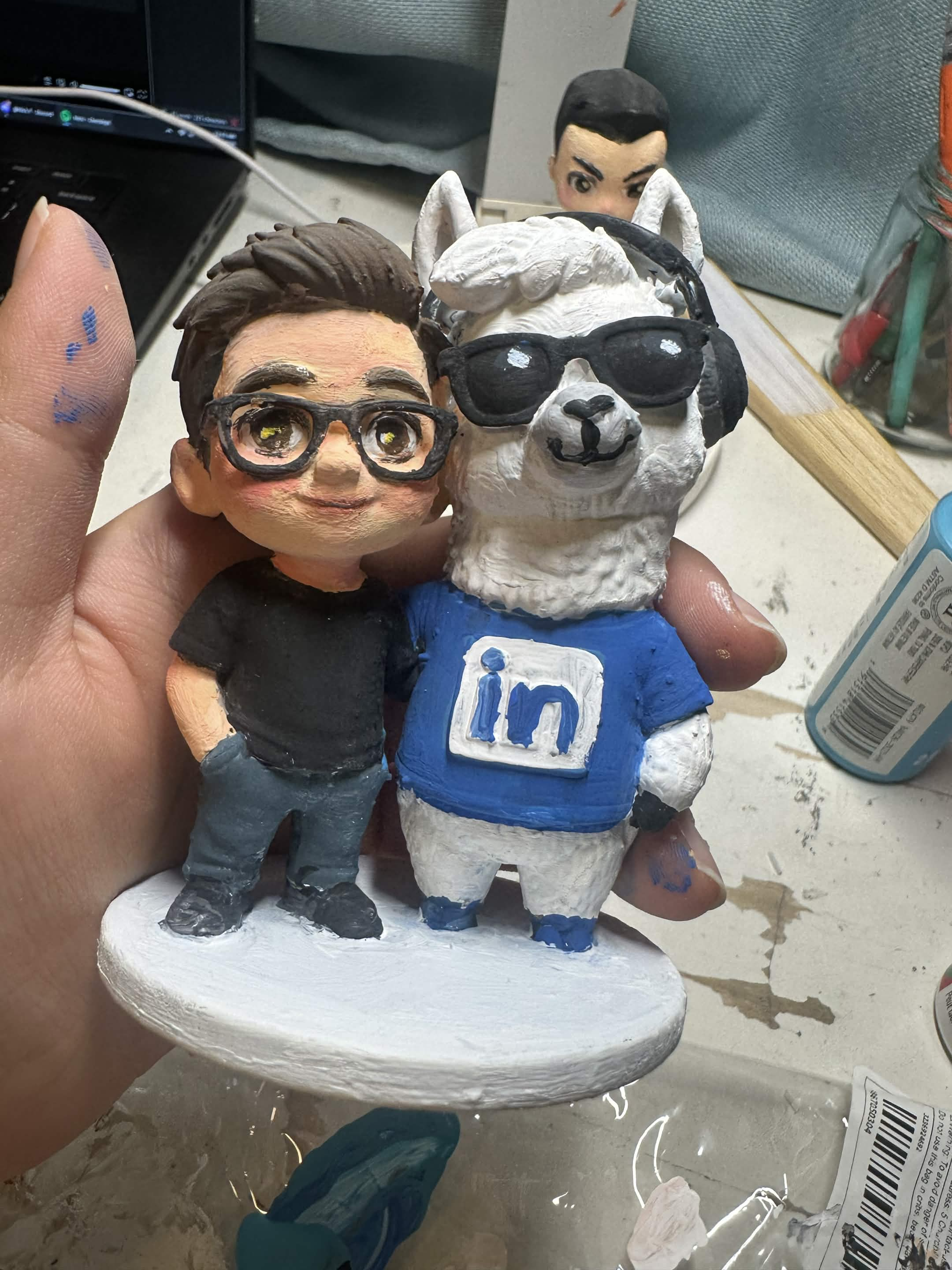 Painted figurine of a person standing beside the LinkedIn llama mascot in a LinkedIn t-shirt